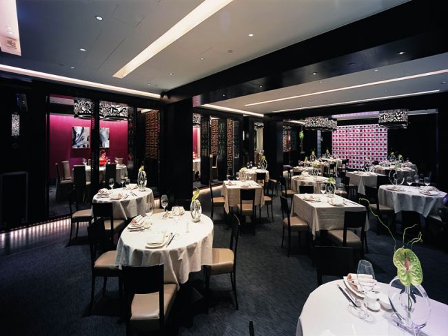 餐厅装修深色调餐区，暗红色金丝绒装饰墙面。