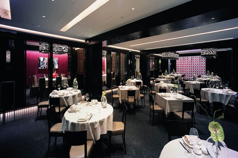 餐厅装修深色调餐区，暗红色金丝绒装饰墙面。